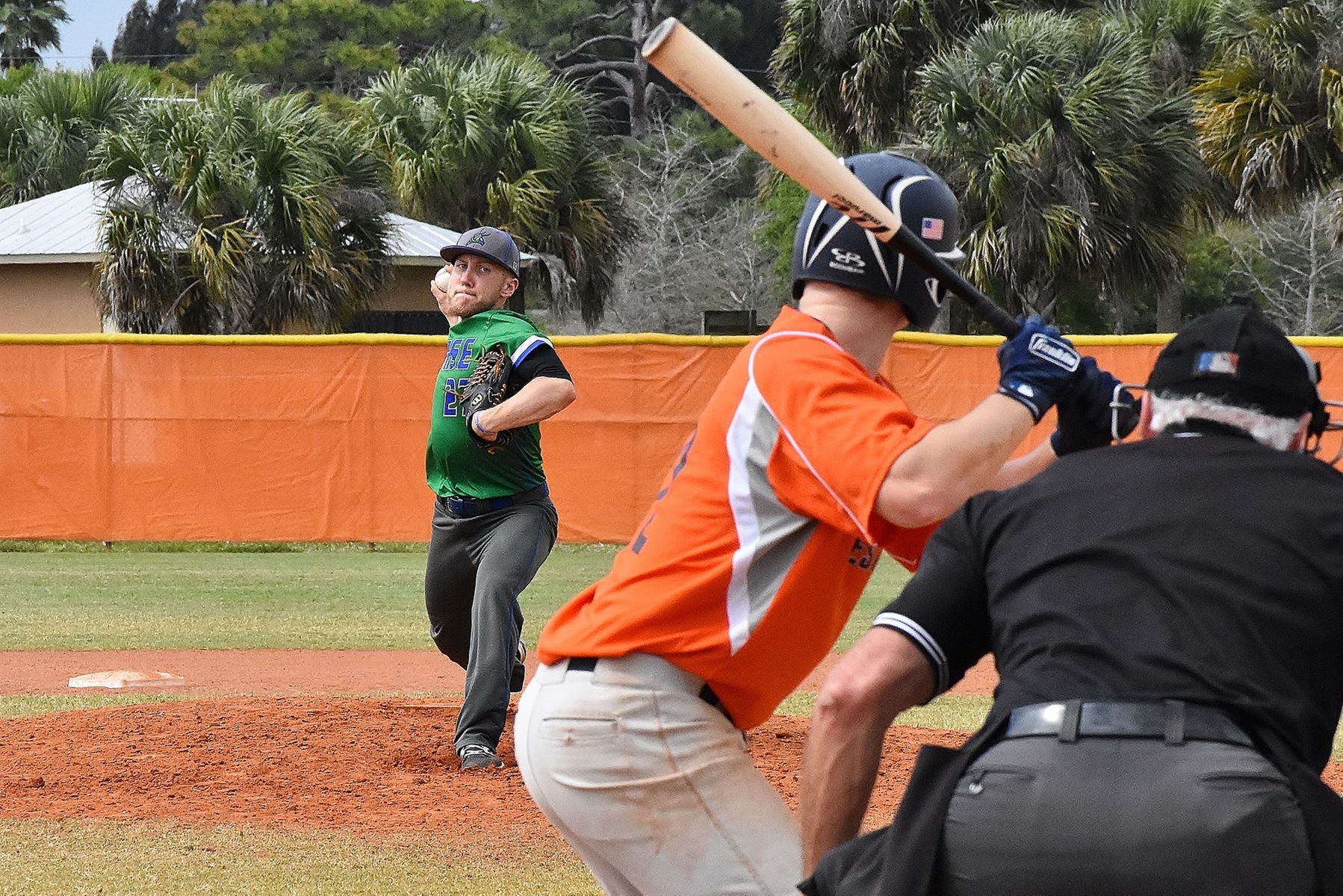 Behind the plate view of Tyler Skufca about to relase a pitch, batter and umpire can be seen in foreground