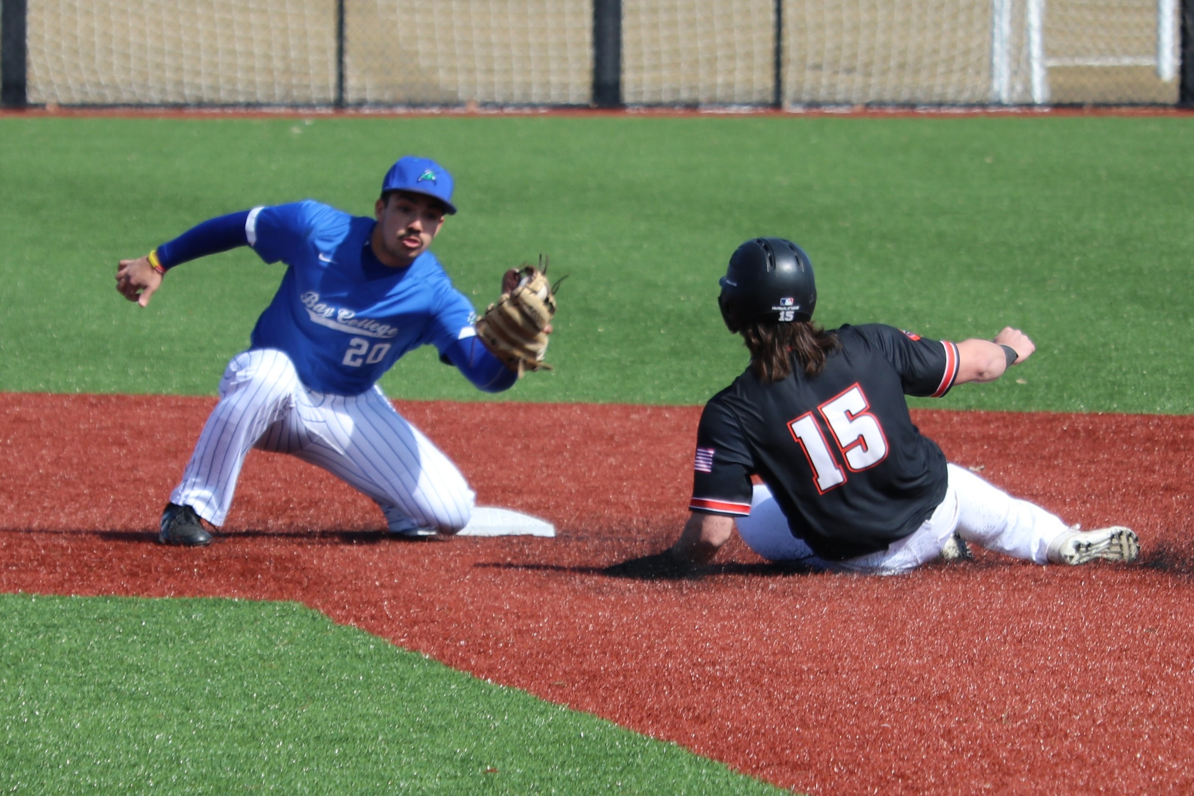 Hector Araguayan on a knee, after having just received a throw at second, as he goes to apply the tag on a runner sliding in.