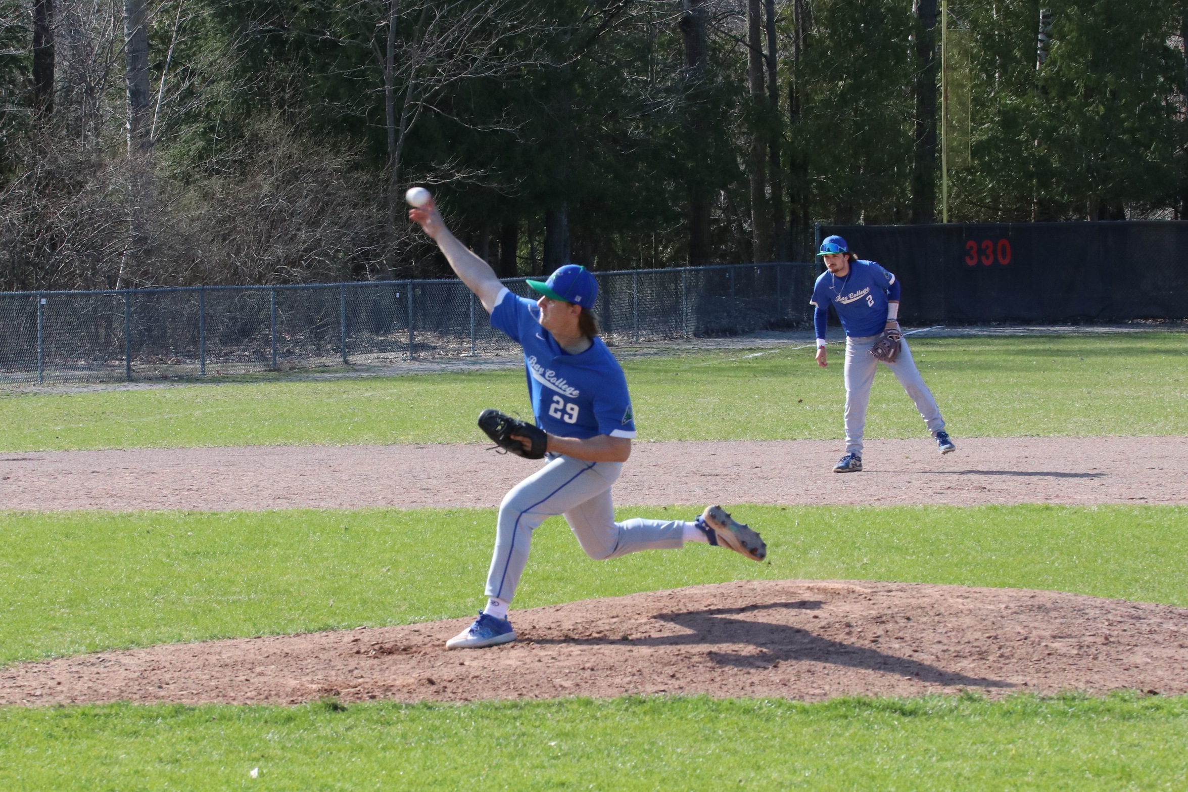 Hunter Ballantyne just releasing a pitch, Josh Blake watches in the background