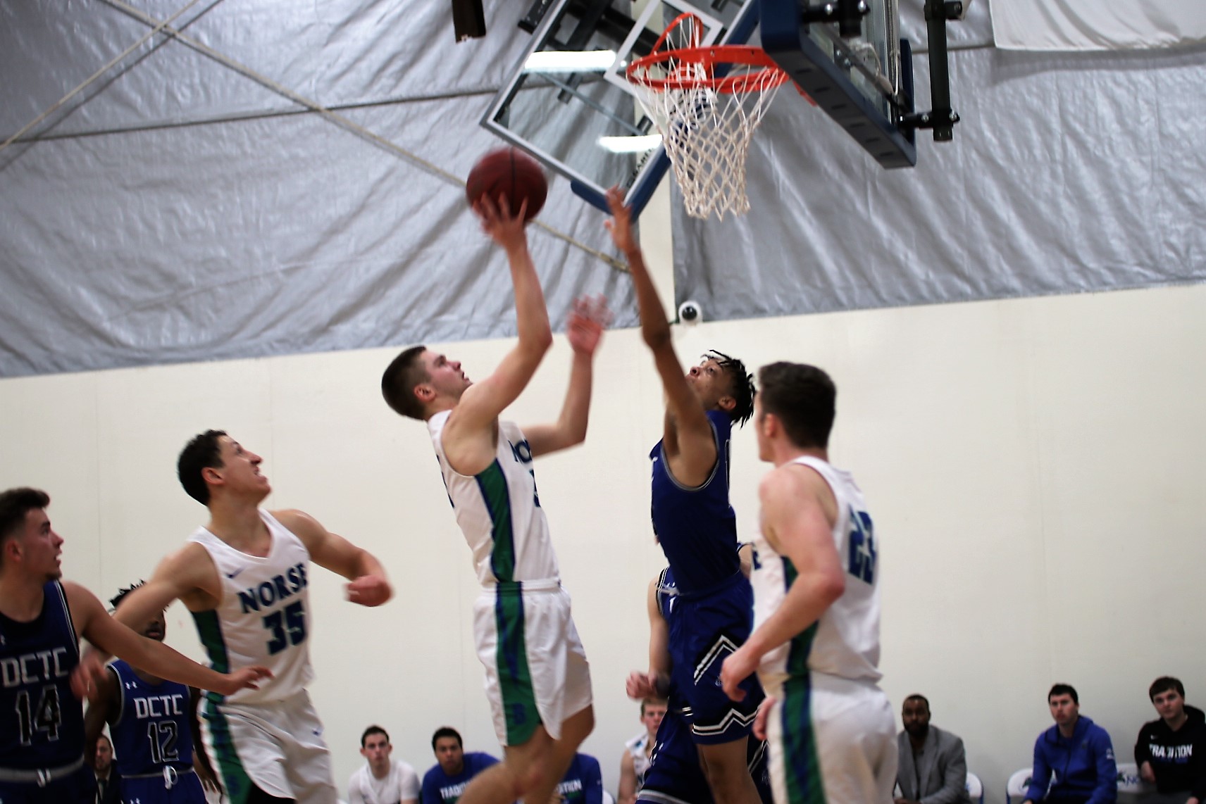 Tyler Willette shooting from the lane, a defender with an arm up, and teammates looking on