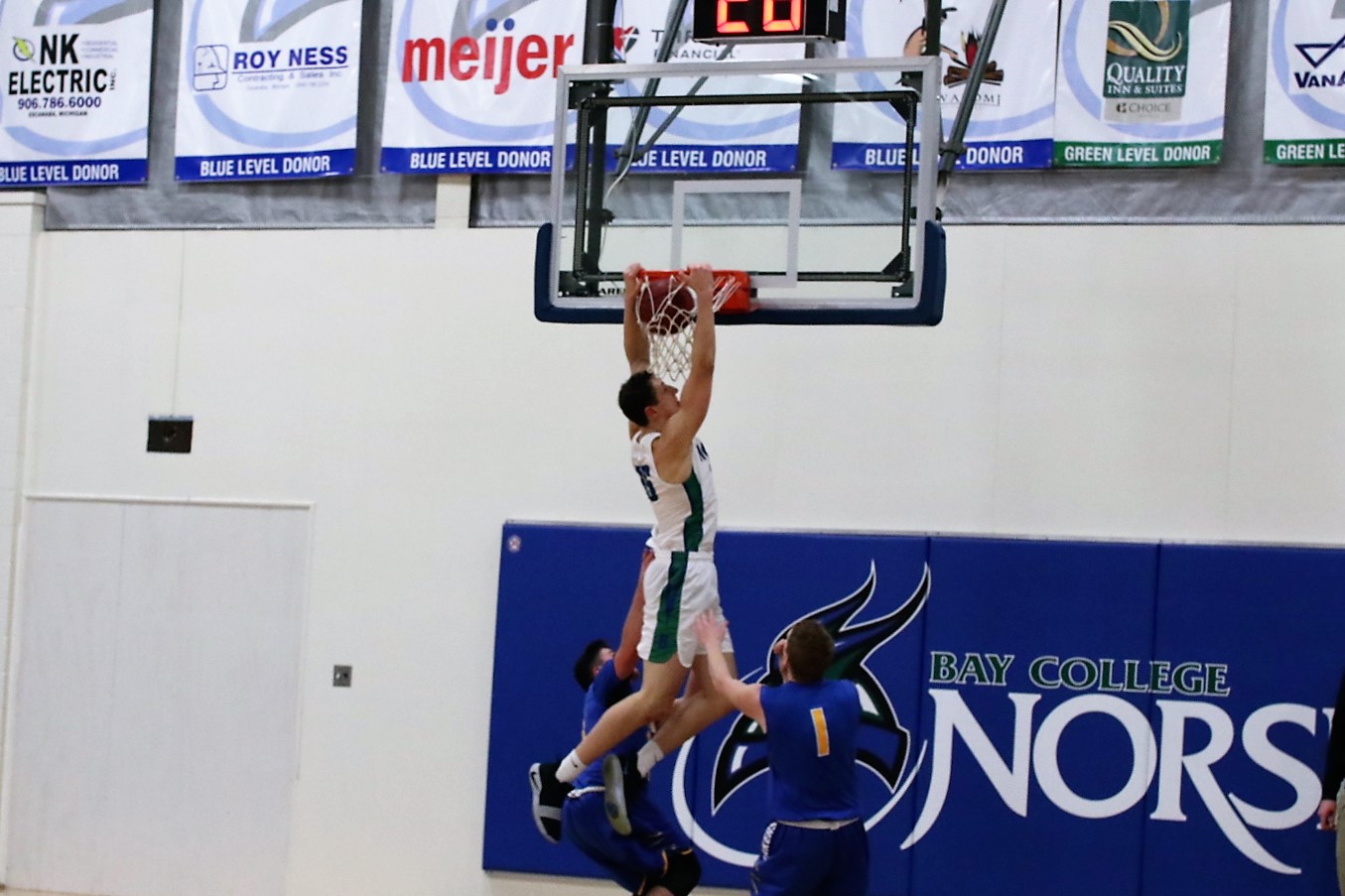 Christian Alexander dunks the ball while two defenders watch from below