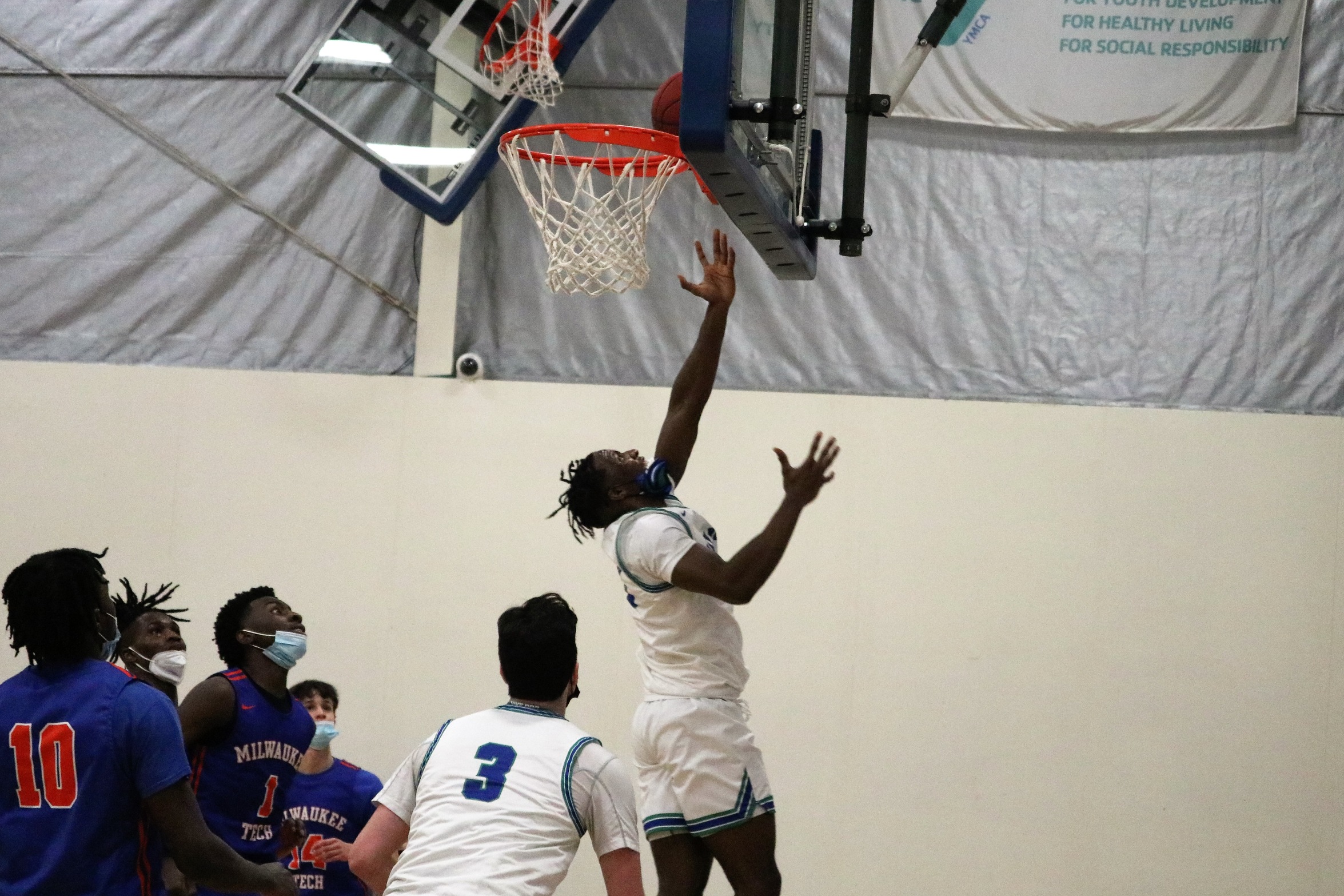 Chris Dobessi lays a shot up at the rim while Joe Gibbs and a host of defenders looks on
