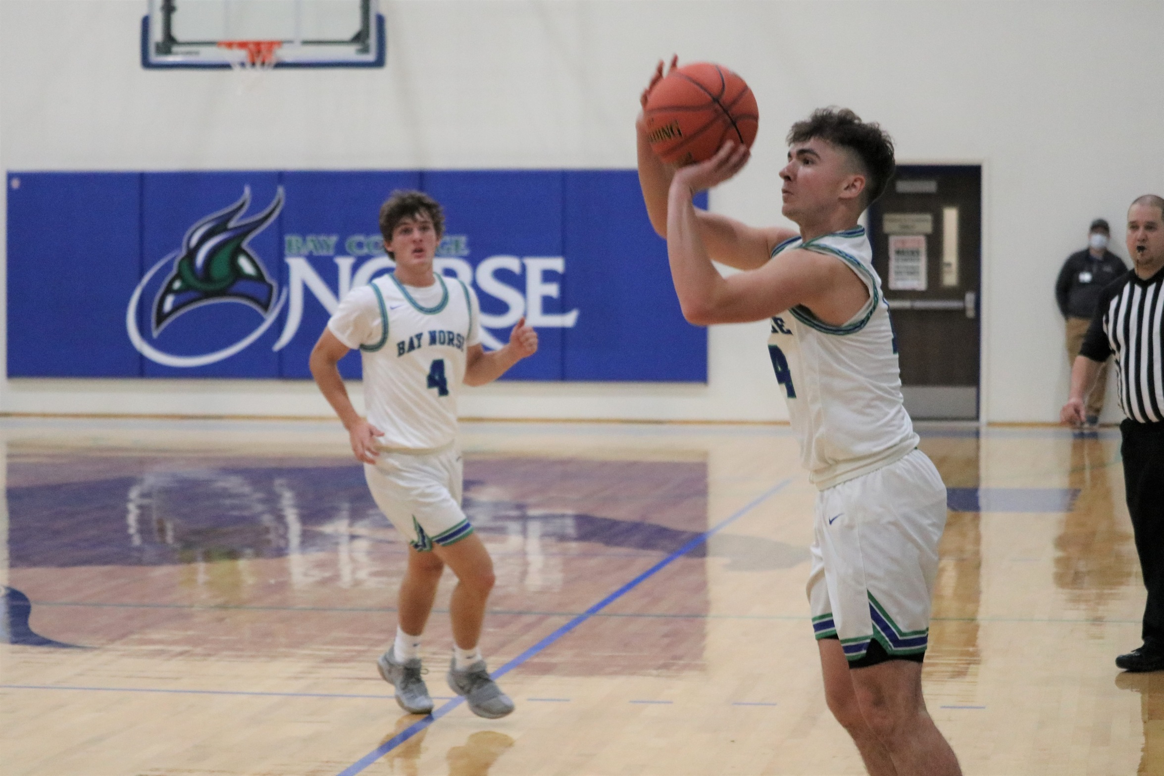 Davin Hill about to release a three-point shot as Parker Maki looks on 