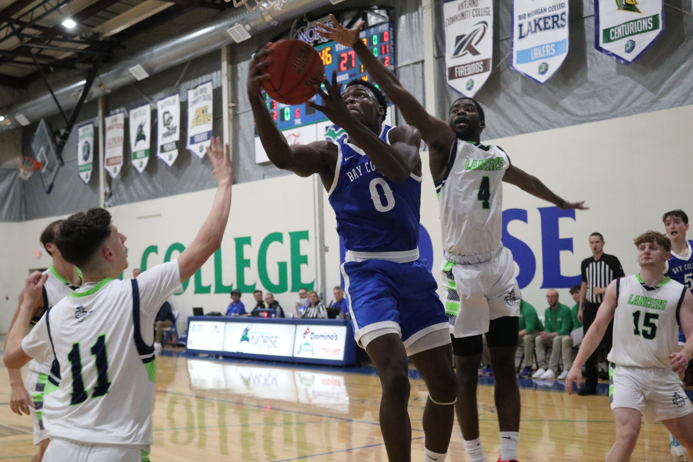 Baril Mawo jumps to shoot a shot with two defenders looking on
