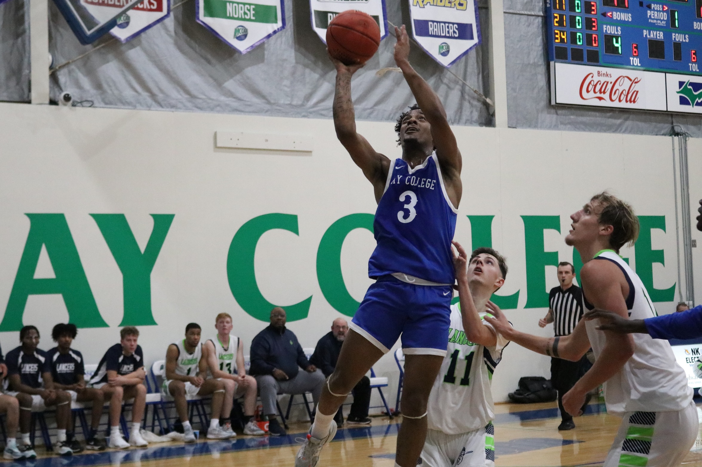 Kairee Gadson releasing a layup as two defenders look on
