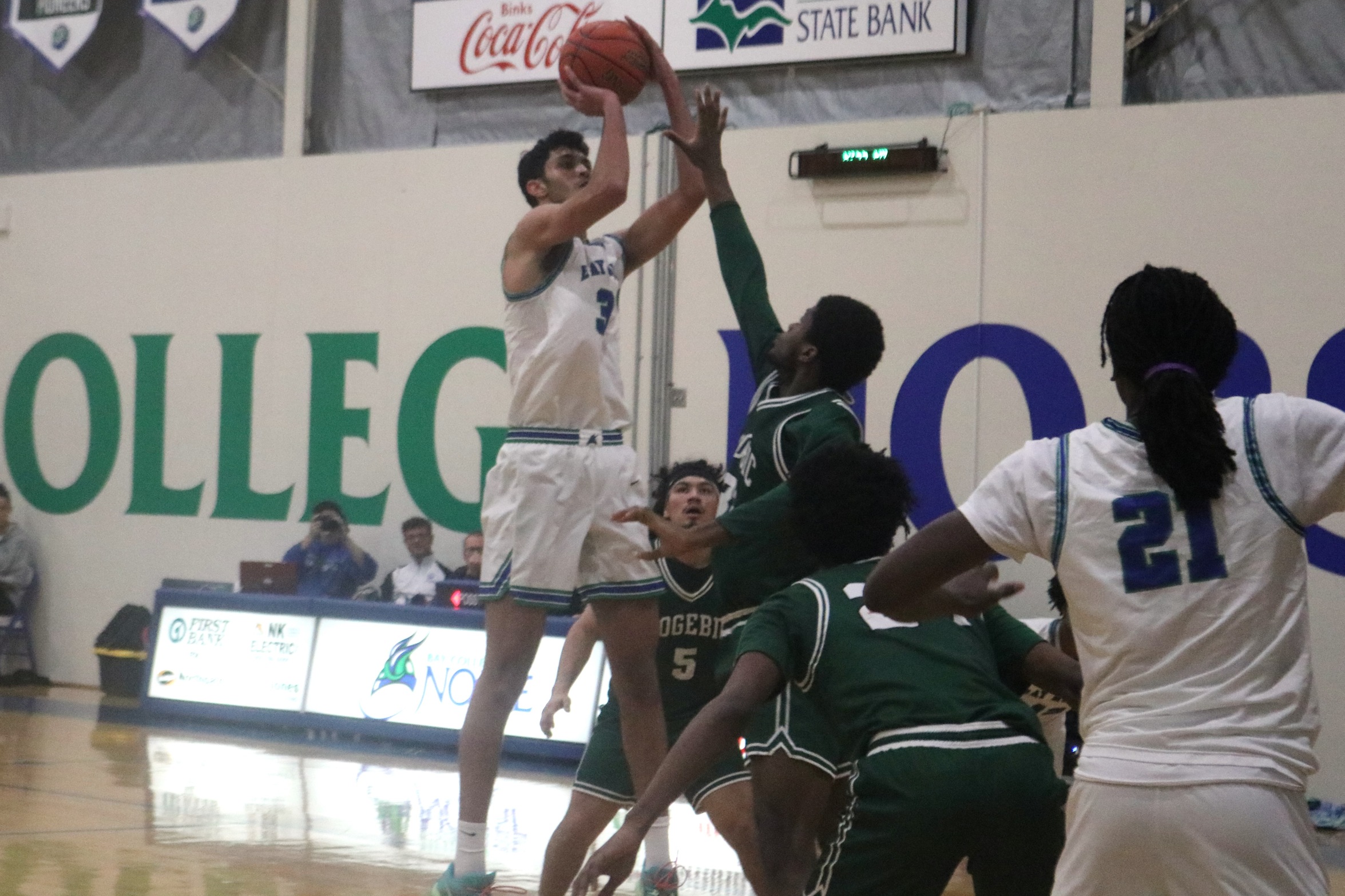 Ziad Abouali in the air to shoot a jumper, a defender is close by with a hand up
