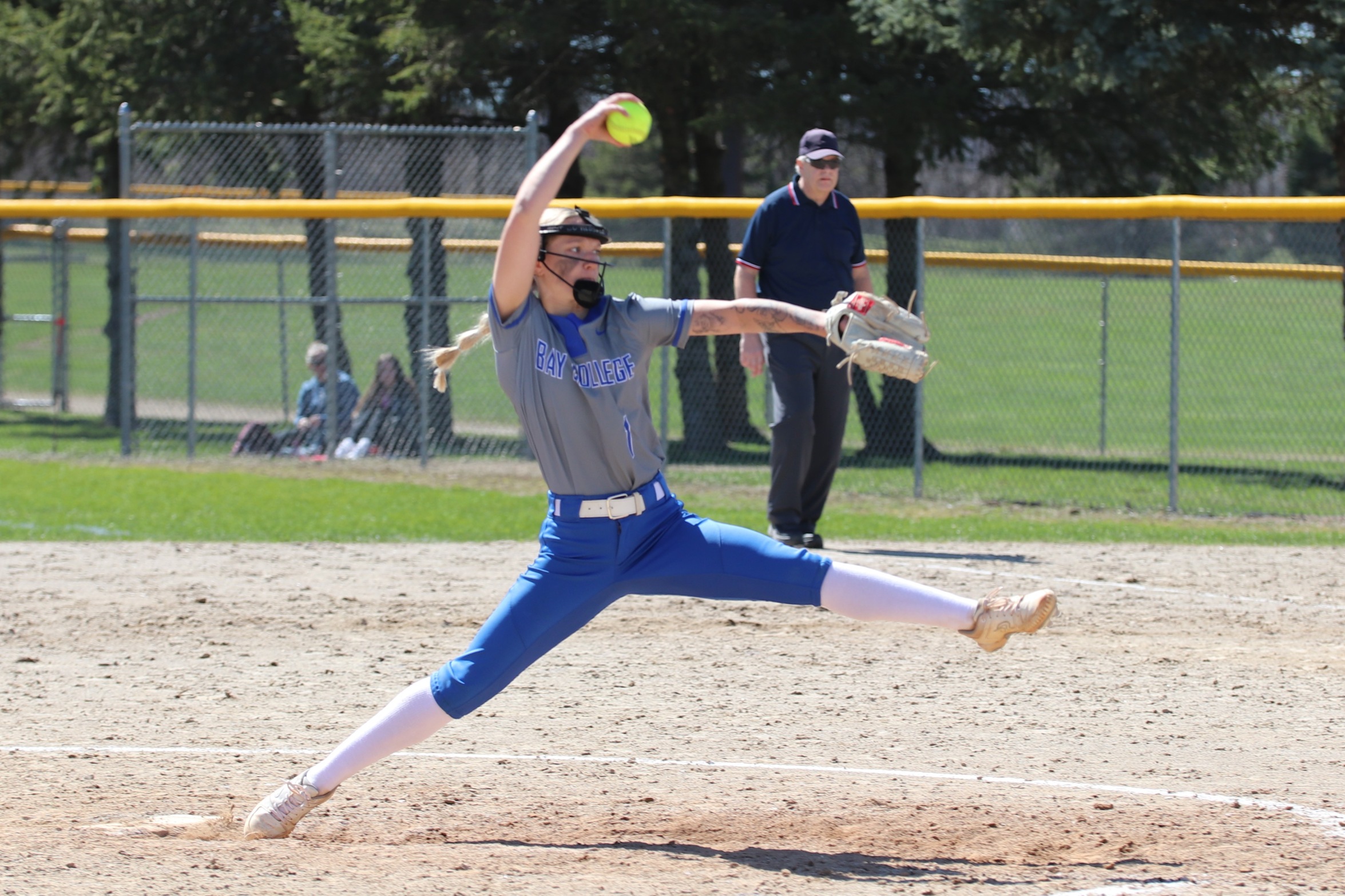 Izzy Drabant in mid pitch, the ball above her head, striding out from the rubber