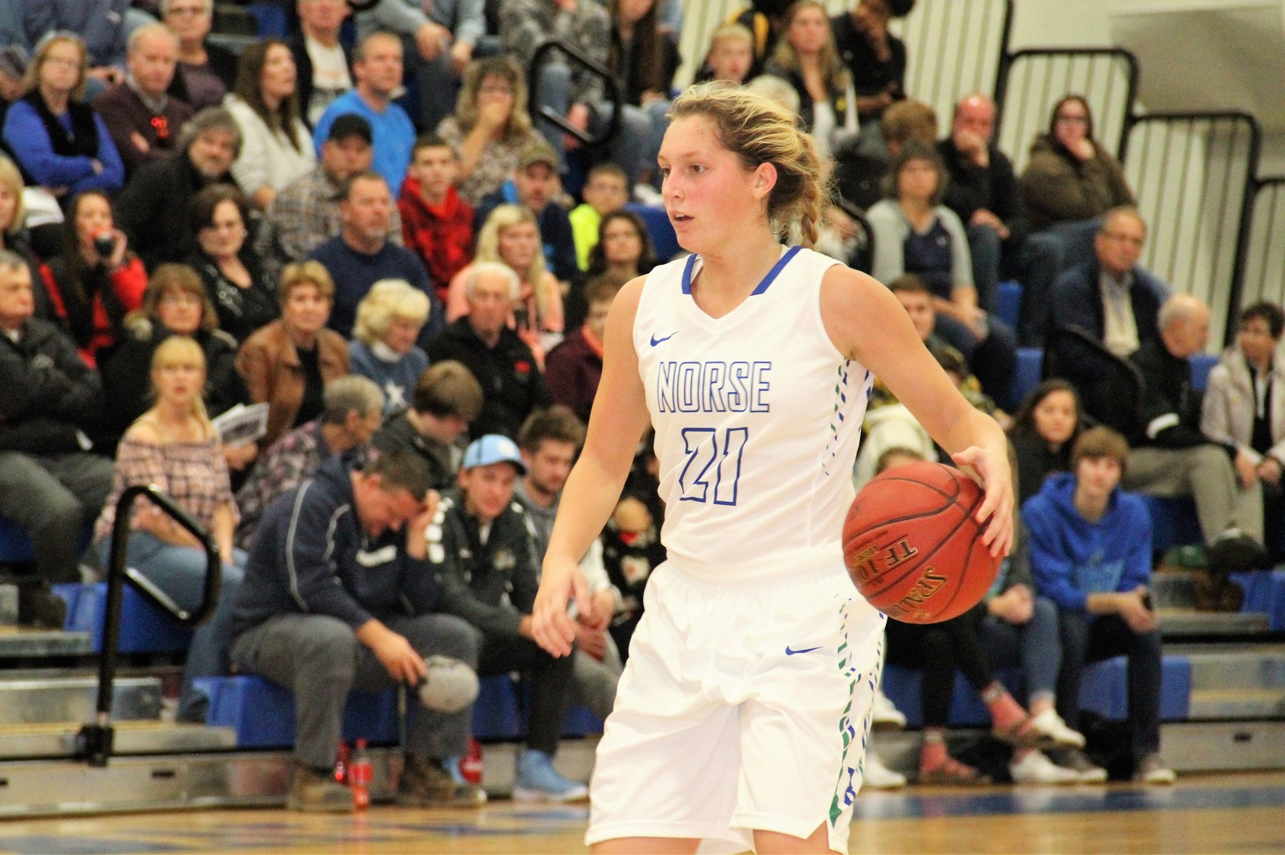 Jordan Kraemer dribbles with her left hand, a full capacity crowd looks on