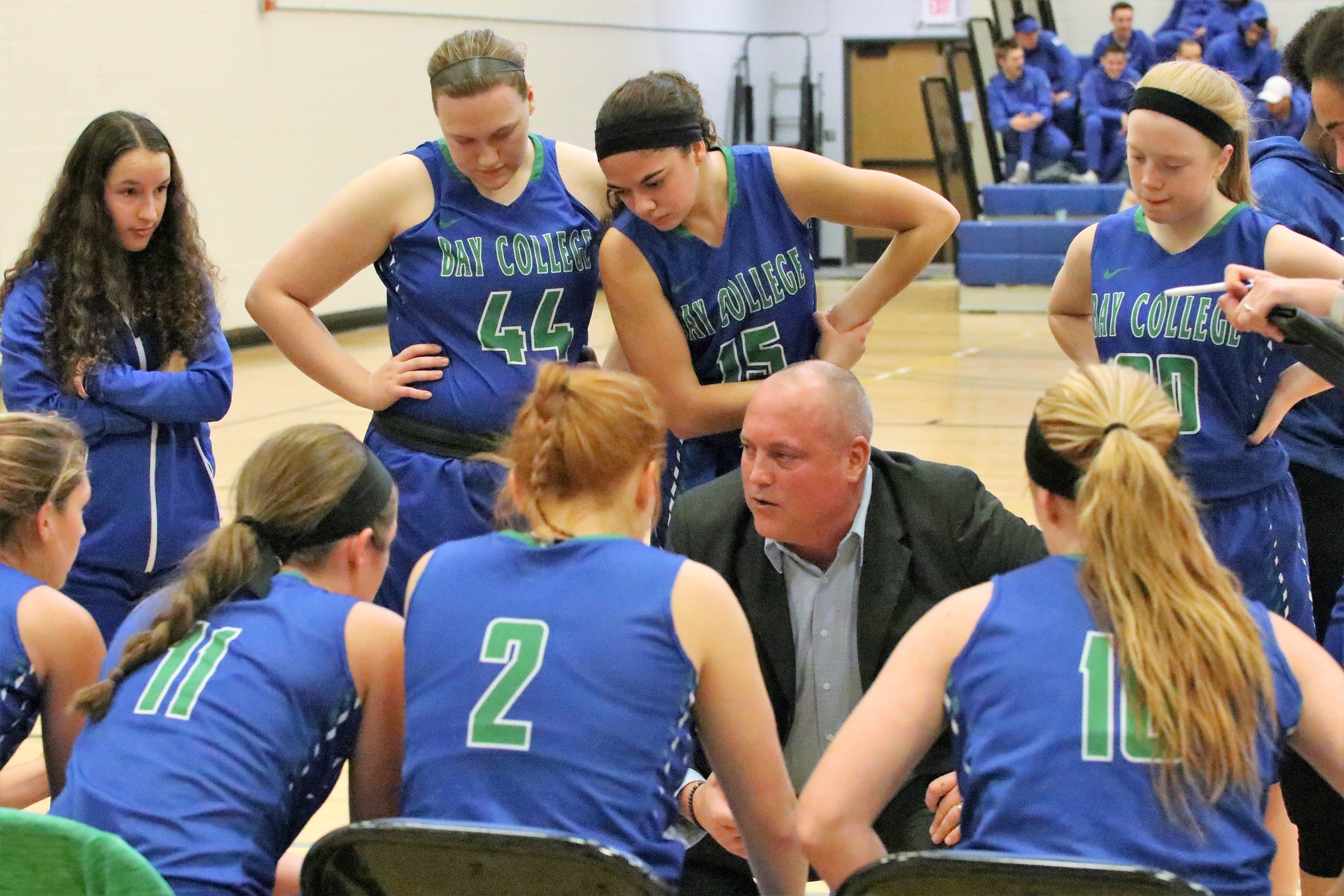 Rob Robinson kneels in a player huddle as his players gather around him