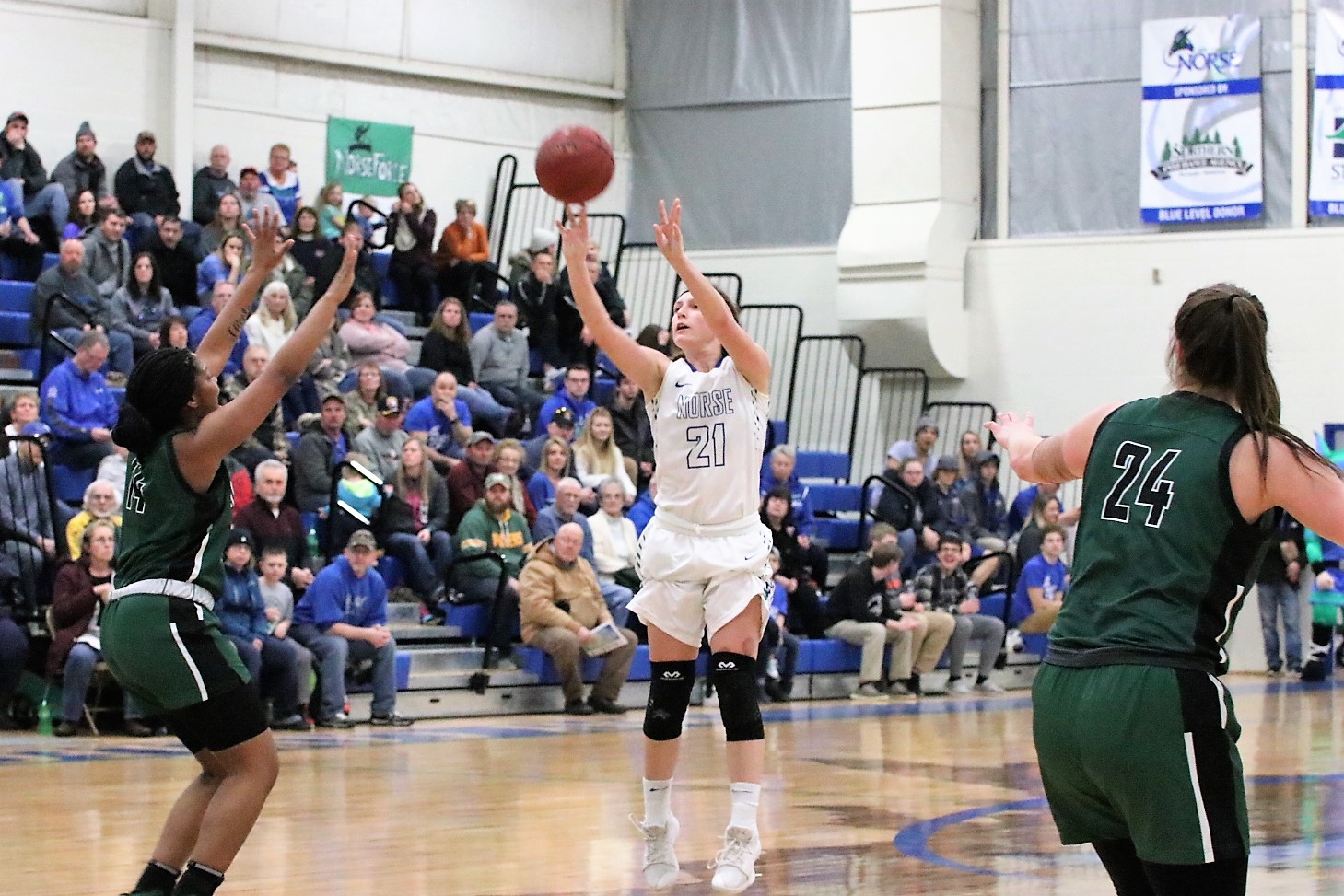 Jordan Kraemer shooting a jump shot.  The ball is just leaving her fingertips and a defender is raising her hands