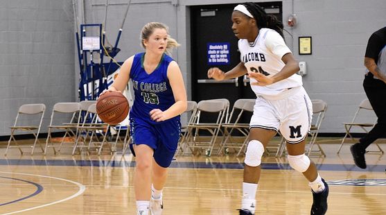 Andie Arsenault dribbles to her right, with a defender closely guarding her.