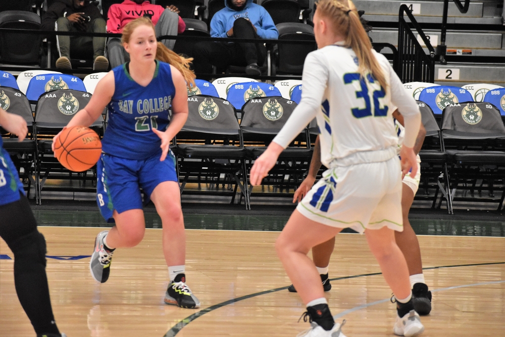 Alaina Trudeau dribbles on the perimeter, as two defenders look on.