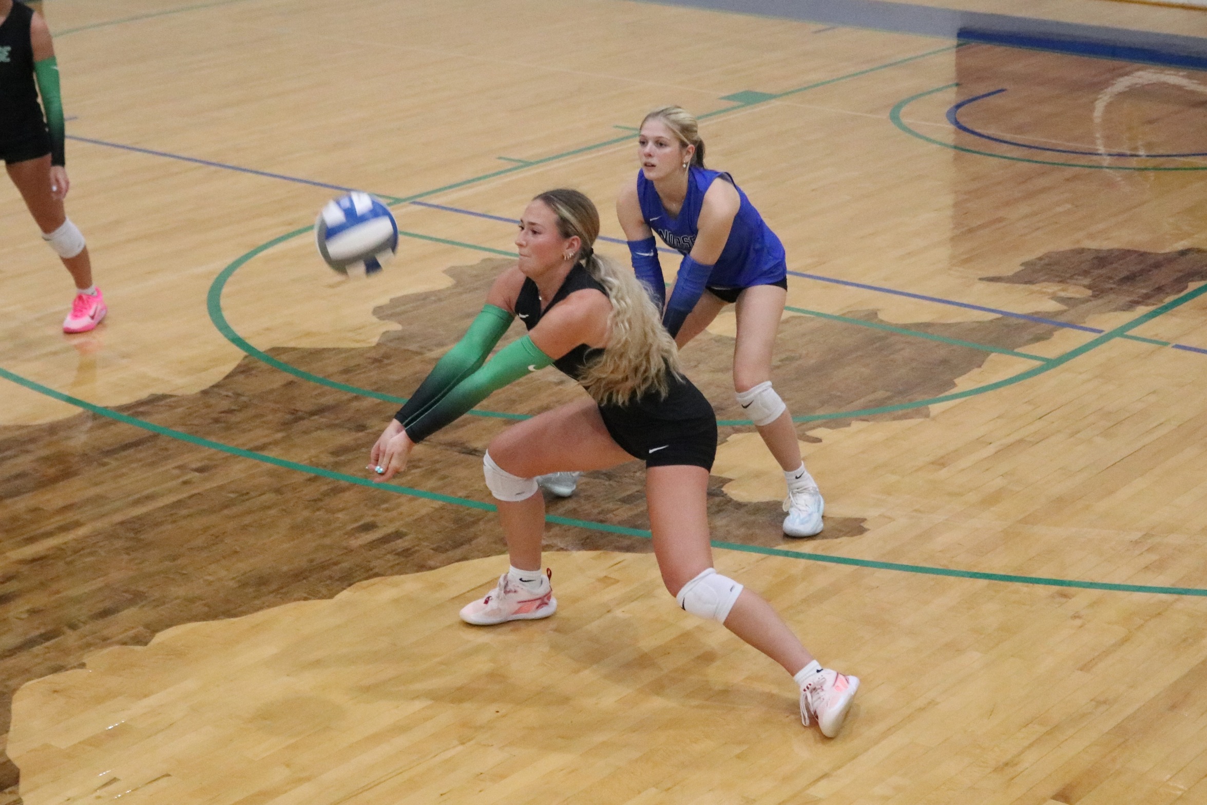 Hilarie Porcaro digging out a ball as a teammate looks on
